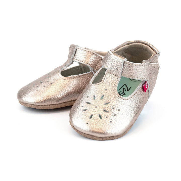 A pair of rose gold leather baby girl's shoes with flowery cutouts on the toes and an adjustable hook and loop strap.