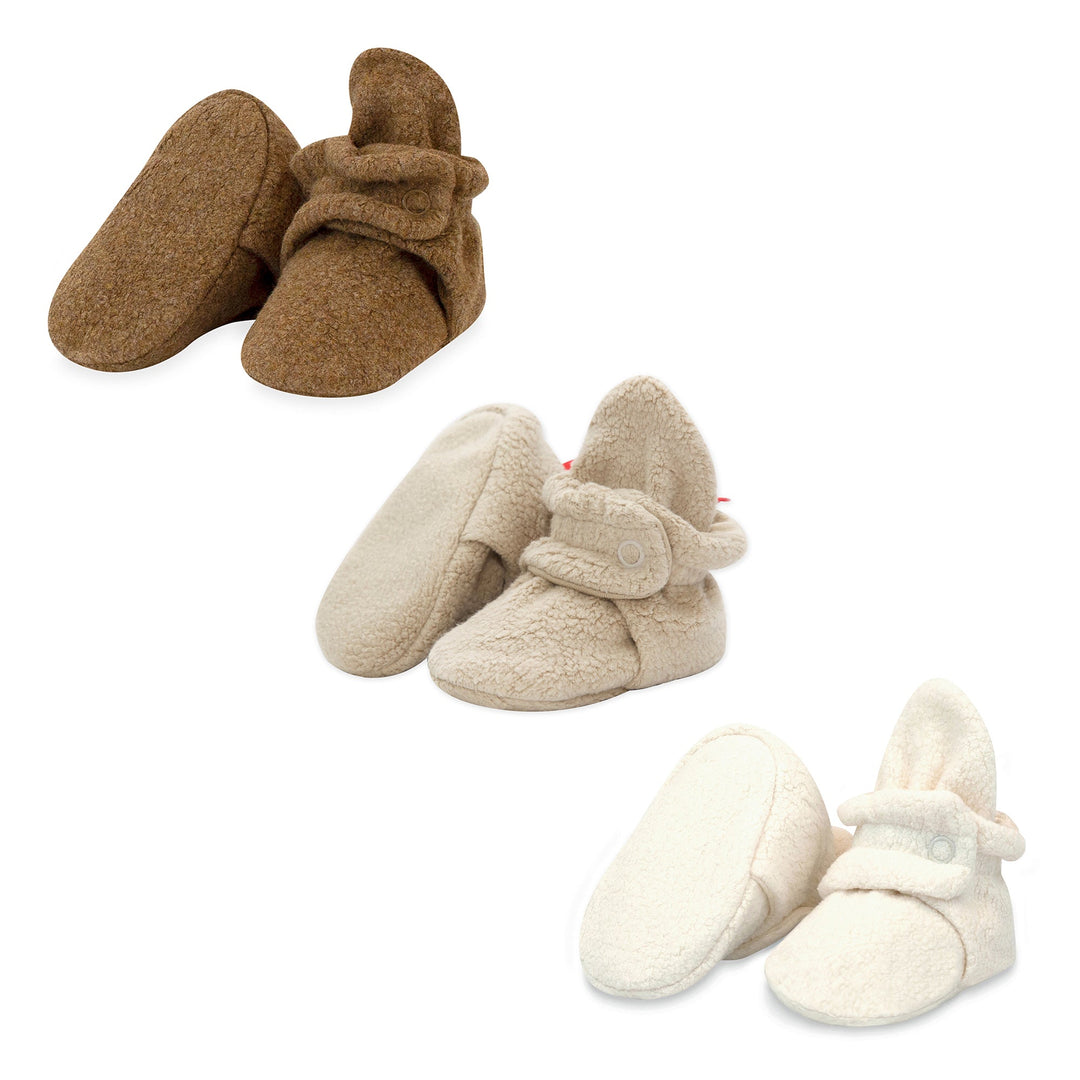 Three pairs of fleece baby booties in colors heather mocha, khaki, and cream, displayed against a white background.