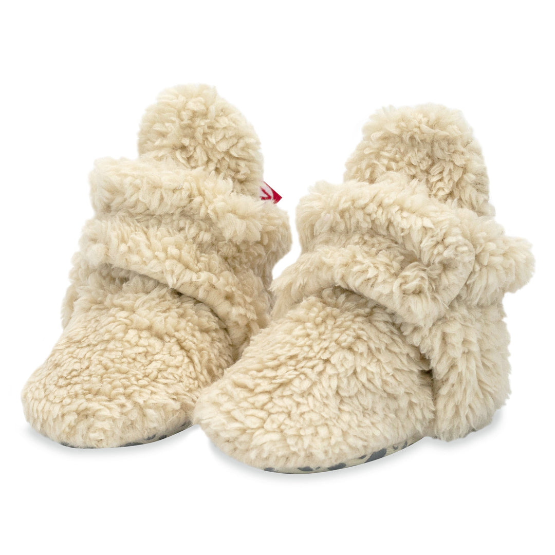 Set of beige furry booties and a matching hat made from organic cotton. 