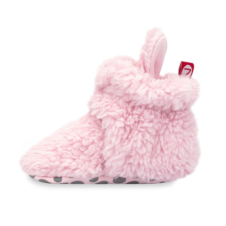 A set of pink baby booties with faux fur exterior and gripper soles, displayed against a white background.