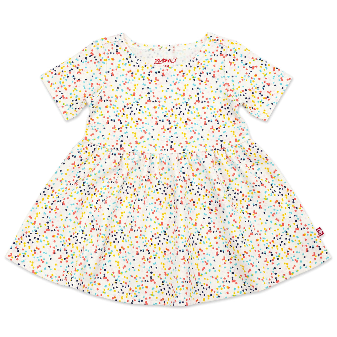 A short sleeve baby dress with a confetti print in various colors on a cream background.