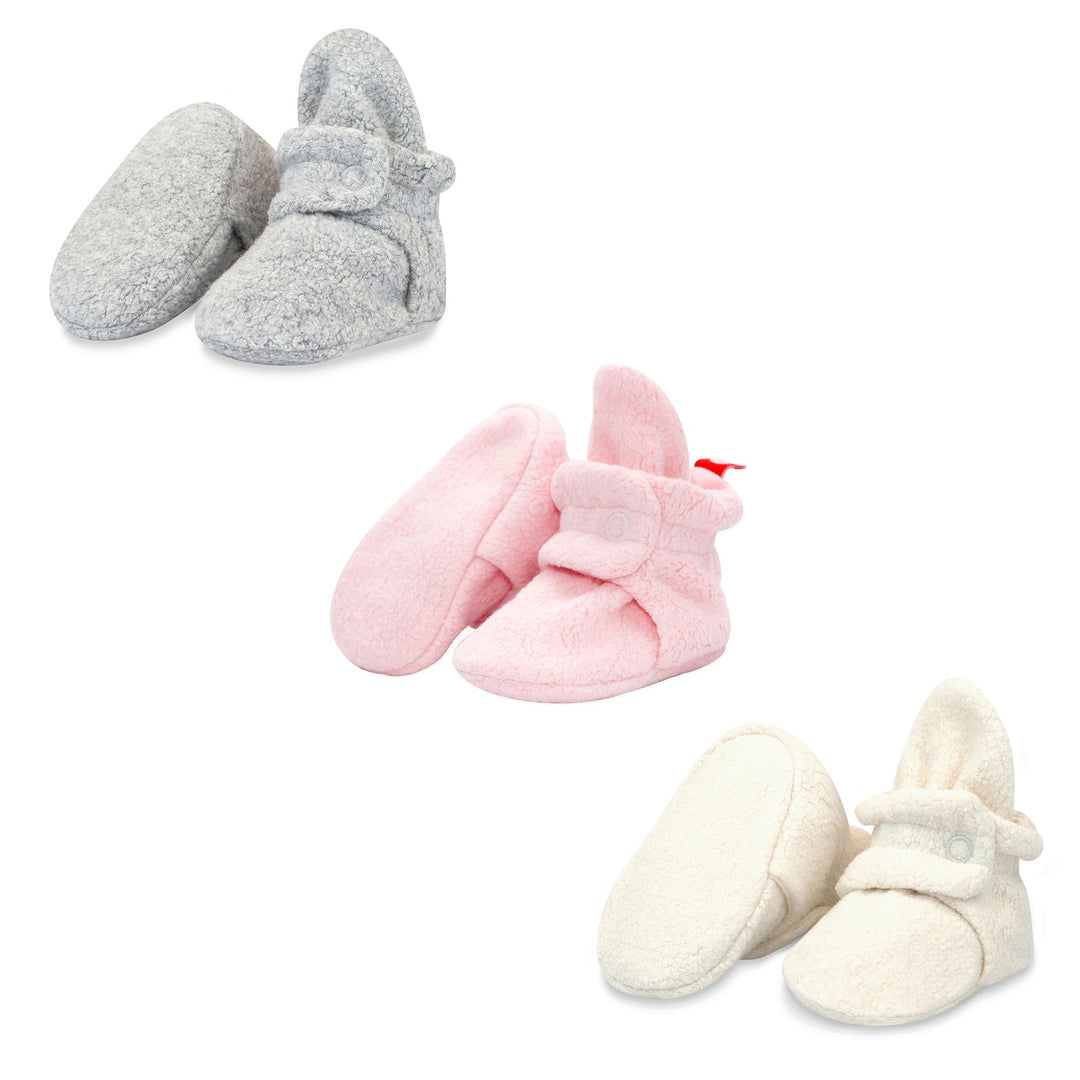 Three pairs of baby booties in a 3 pack, with one pair in heather gray, another in baby pink, and the last in cream color.