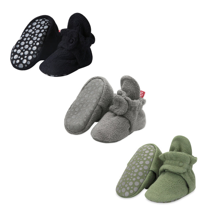 Three pairs of fleece baby booties in black, gray, and olive colors, displayed separately against a white background.