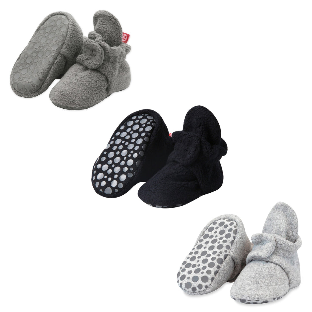 Three pairs of fleece baby booties in gray, black, and heather gray colors, displayed with gripper soles visible.
