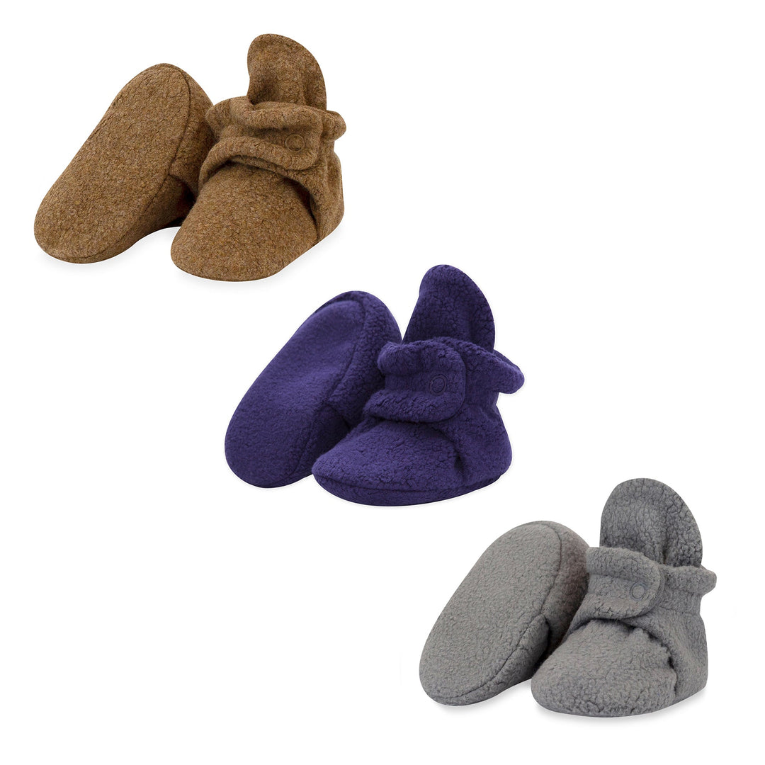 Three pairs of fleece baby booties in colors heather mocha, true navy, and gray, each pair with adjustable snaps and a soft appearance.