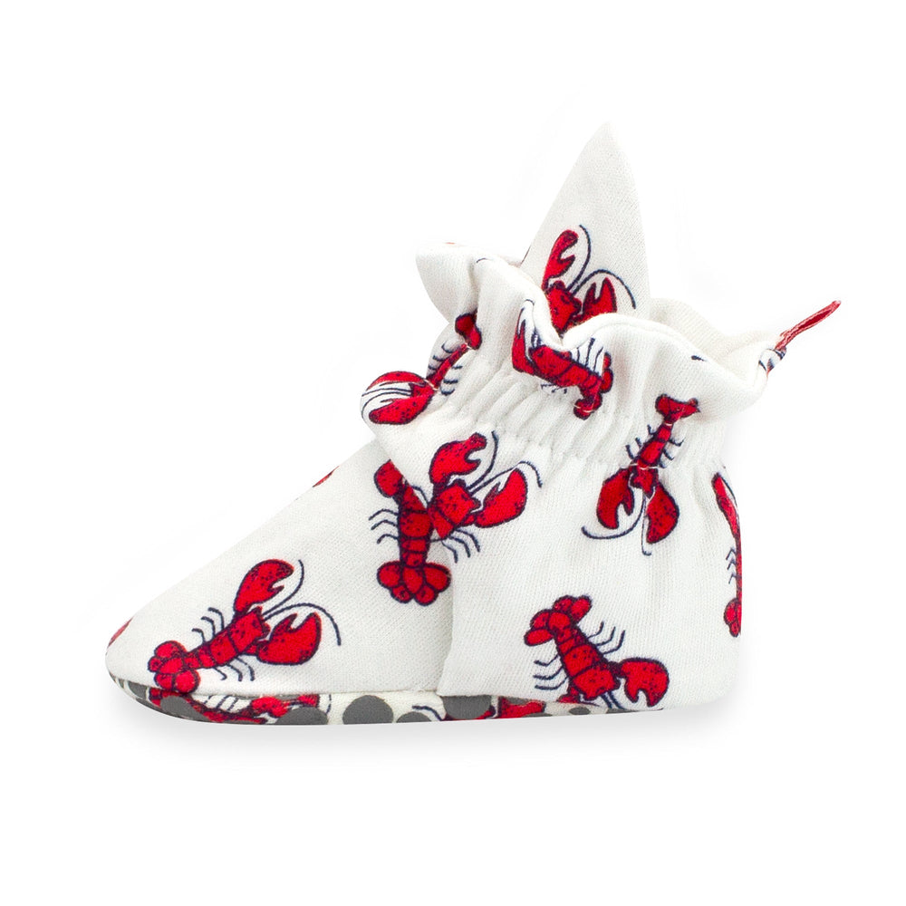 Set of white baby booties with a red lobster print and gray dots, featuring rubber grippers on the bottom.