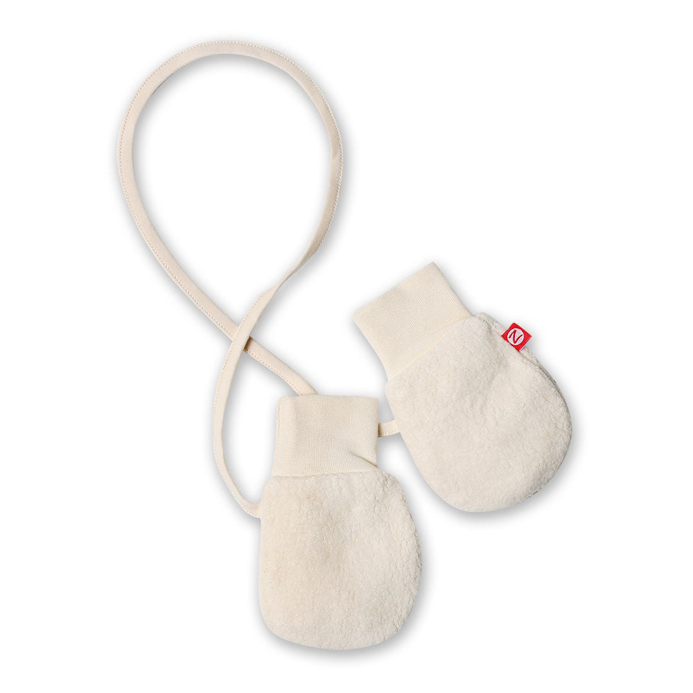 A pair of cream-colored Zutano cozie fleece baby mittens with a cuff and a small red tag visible.